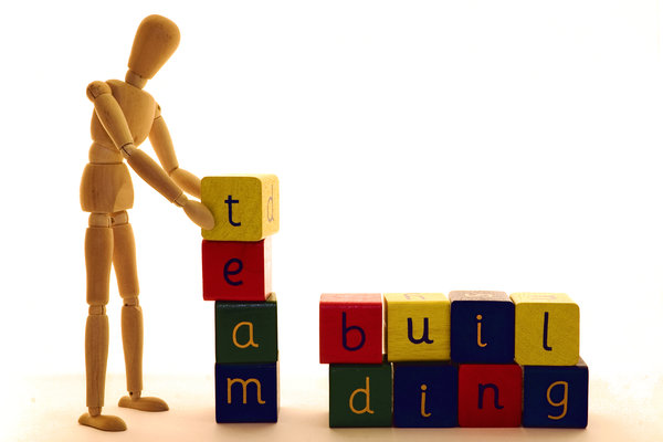 Team Building: Wooden artist's model demonstrating the art of team building with alphabet blocks.