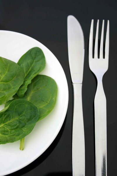 Spinach Diet: Spinach leaves on a white plate with knife and fork