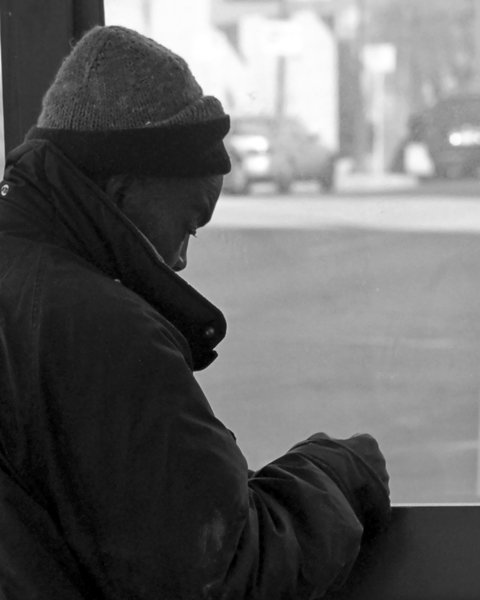Bus Shelter: Homeless man using bus shelter as shield against cold wind