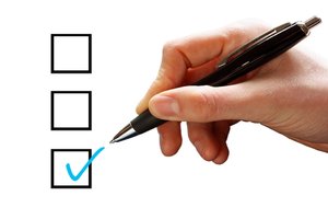 Tick Box: Hand with a pen and a blue tick in a box on a white background