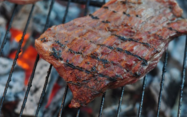 Grilled steak: Closeup of a steak on the grill, with fire in the background