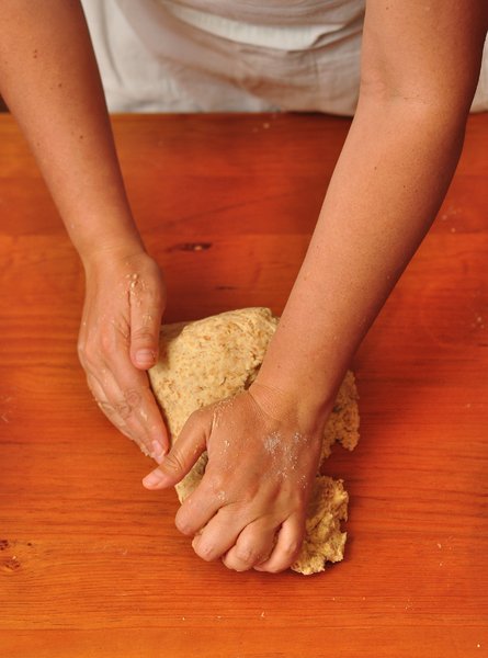 Kneading Pizza dough: Woman kneading whole-wheat pizza dough on a wooden table