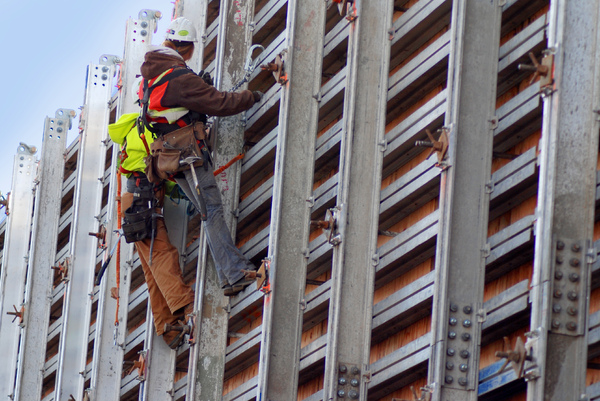 Construction crew: Construction workers harnessed to a wall.