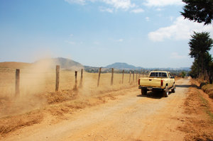 Pick-up truck in dirt road: Pick-up truck passing by in a dirt road in the country, midday