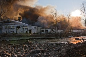 Inferno: Figher Fighters battle a Factory warehouse fire at sunset across a stream. Taken in Cornwall, New York. Contact me for Hi-Res.
