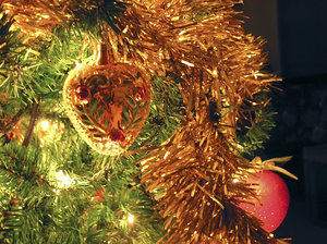 Antique Ornament and Garland: An antique ornament and garland on a Christmas tree with a golden glow.