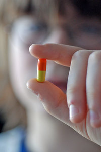 Medicine in capsule: Two colours pill in fingers of young boy