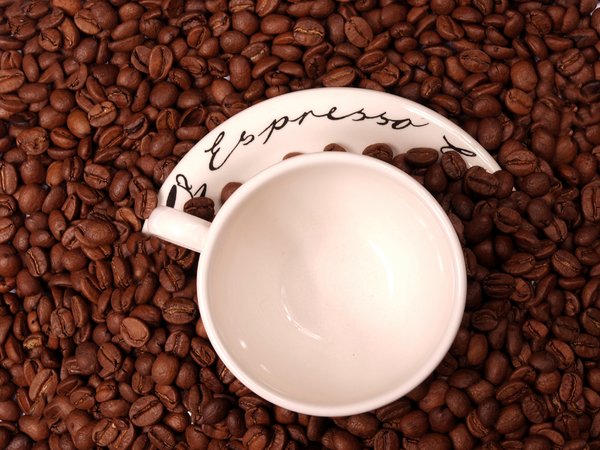 Coffee beans and an espresso c: An espresso cup and saucer in coffee beans