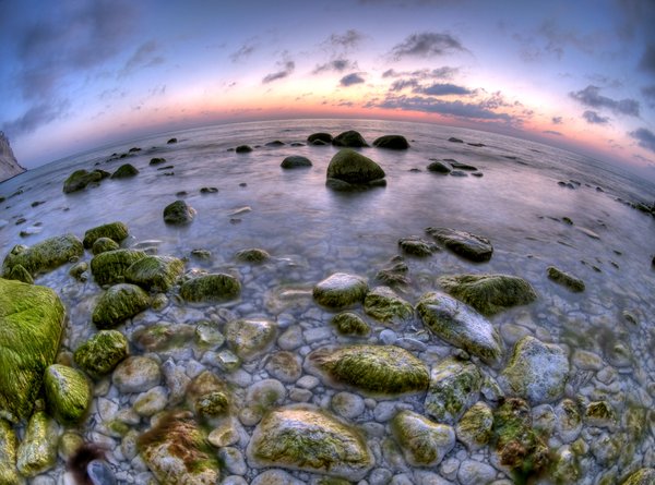 First light - HDR: The light before sunrise showing chalkrocks in the ocean, the pale morning sky and a chalkcliff. The picture is HDR using a fisheye lens.