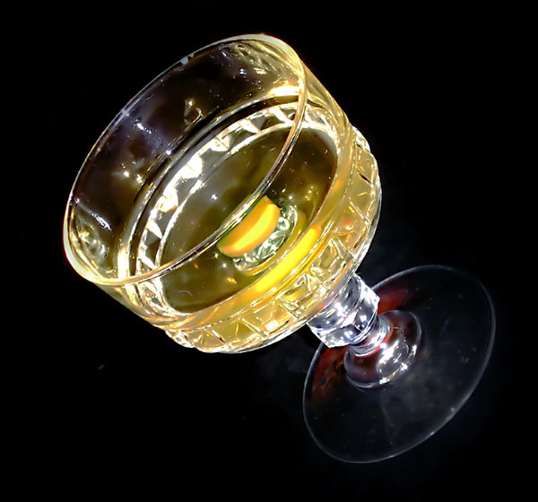 Glass: Crystal glass with yellow alcohol in it on the black background.