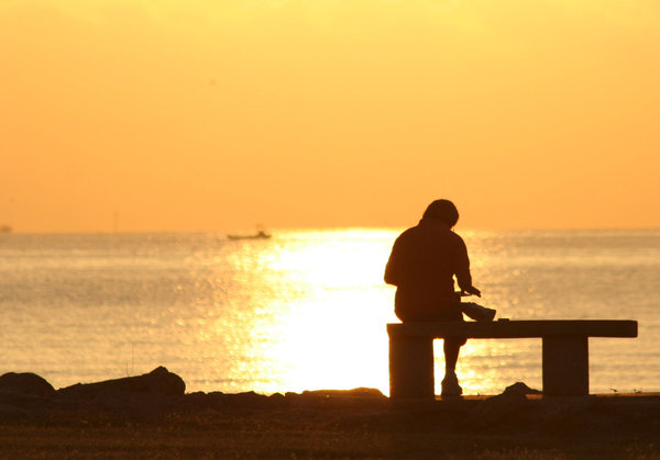 Bible Reader: Man reading his bible at sunrise on Galveston Bay