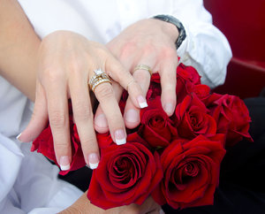 Roses 'n' rings: Hands laid on a red rose bouquet by newly weds.