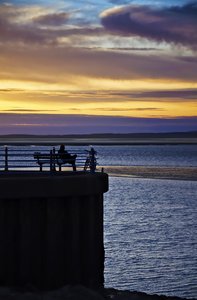 Solitude at sunset: a lone cyclist contemplates life as the sun sets over morecambe bay
