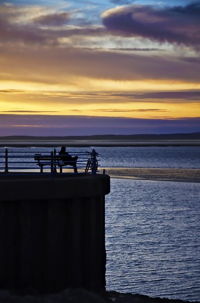 Solitude at sunset: a lone cyclist contemplates life as the sun sets over morecambe bay
