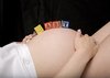 BABY in blocks: Letter blocks spelling BABY, on the belly of a pregnant young woman.