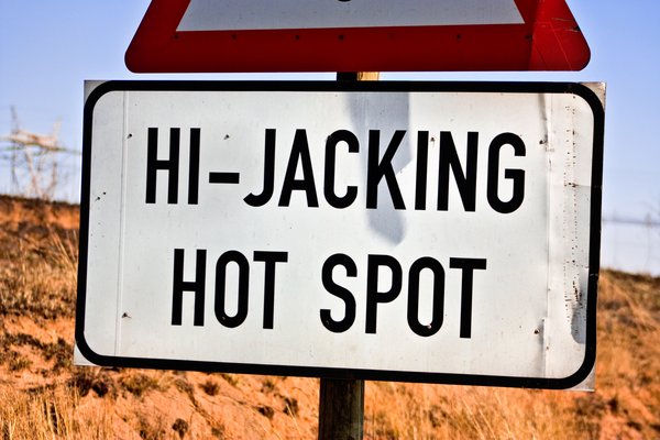 Hi-Jacking Hotspot Sign: Close-up of a highway road sign reading HI-JACKING HOTSPOT located near Witbank, South Africa. A little roughly captured, but I didn't exactly want to stick around too long for reasons apparent on the sign.