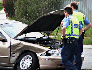 checking the damage: police checking the damage to a motor vehicle involved in a crash