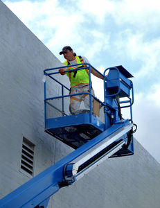 painting on high3: workman painting wall in raised cherry picker