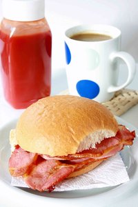 Bacon Roll: Fried bacon roll with a mug of tea and tomato sauce