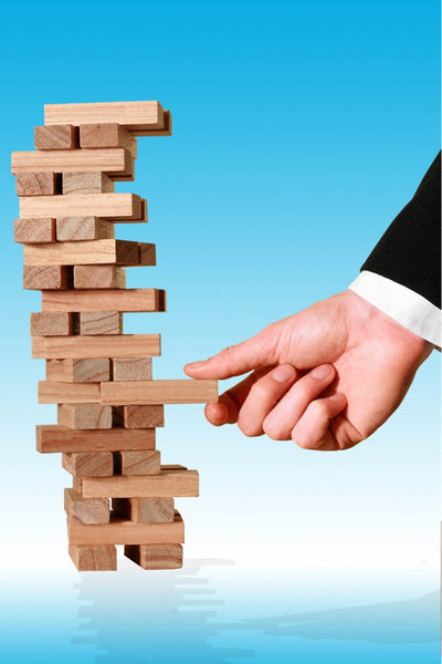 Business Decision: Tower of wooden blocks being removed by a hand
